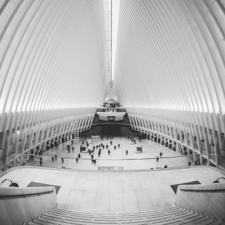 inside-of-an-artistic-building-with-very-large-columns-and-ceiling-with-people-walking-below